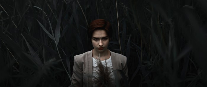 Woman in a jacket standing in dark foliage
