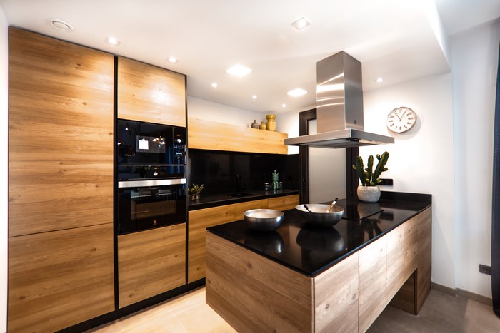 Modern wooden kitchen with black granite island and ovens