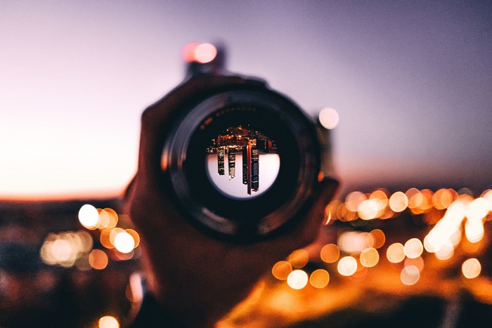 City skyline reflected in a camera lens at dusk