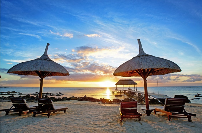 Beach umbrellas and lounge chairs at sunset in Mauritius