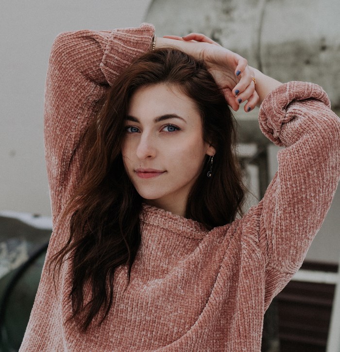 Woman with brown hair wearing a pink sweater