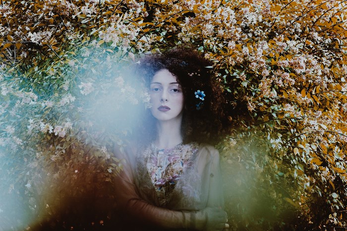 Woman with curly hair and flowers in a garden