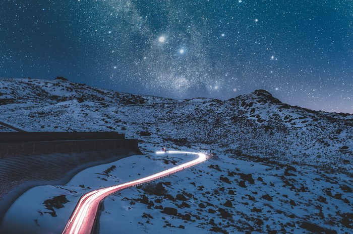 Snowy mountain road under a starry night sky
