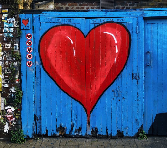 Street art of a large red heart on a blue wooden door in London