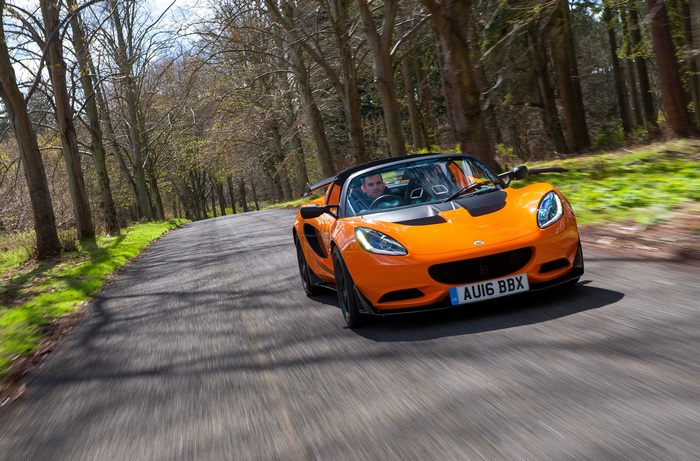 Orange Lotus Elise Cup 250 driving on a tree-lined road