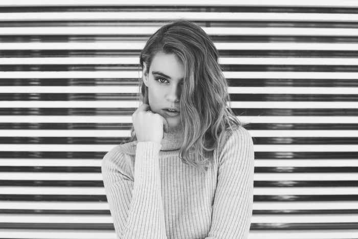 Woman in turtleneck posing against striped wall