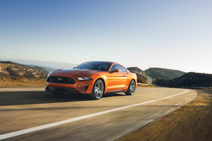 Orange Ford Mustang driving on a winding road