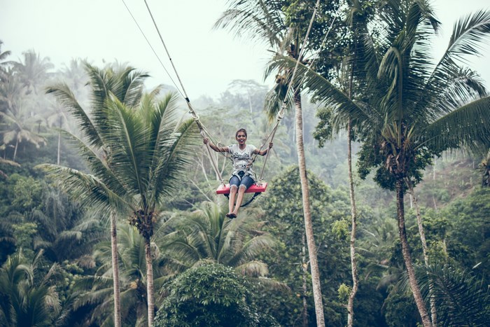 Woman swinging on a swing in a tropical forest