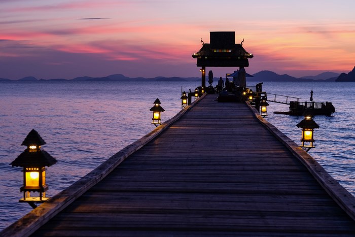 Wooden pier with lanterns at sunset in Thailand