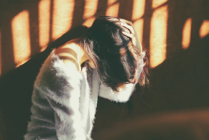 Woman with hand on head in sunlight and shadow