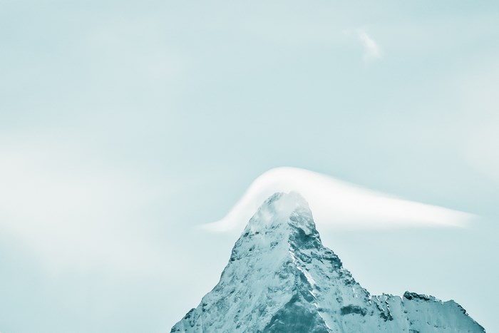 Snowy mountain peak with a cloud formation
