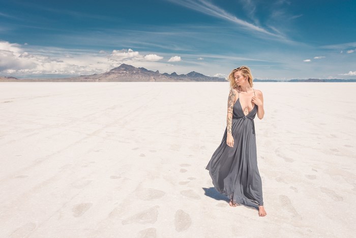 Woman with tattoos on a salt flat with mountains