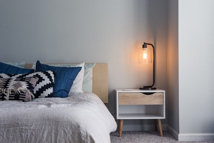 Minimalist bedroom with blue cushions and a bedside lamp