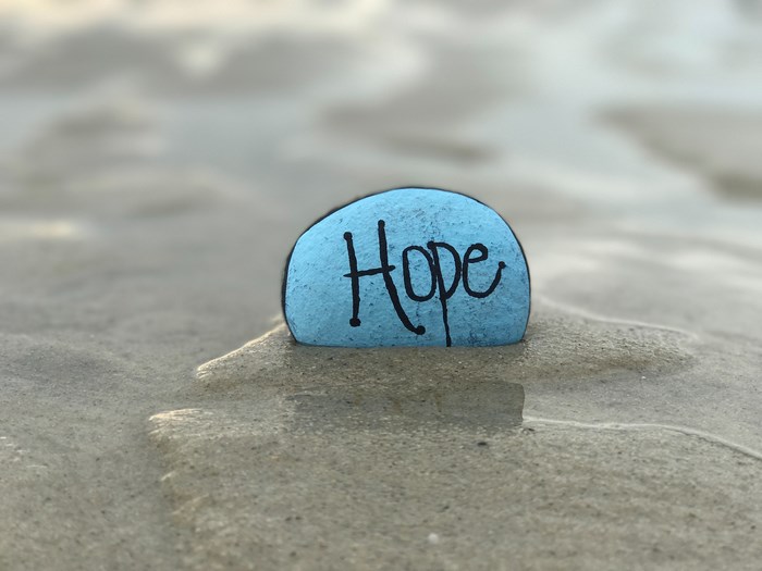 Blue stone with the word "Hope" on sand