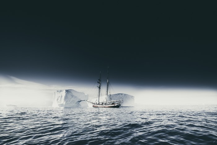 Sailboat navigates icy waters near icebergs