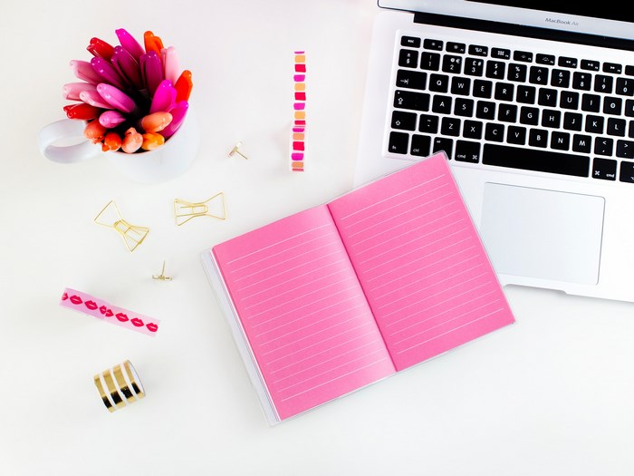 MacBook Air with pink notebook and colorful markers