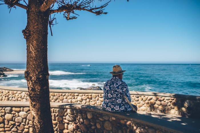 Man in Hawaiian shirt sitting by the ocean in La Jolla