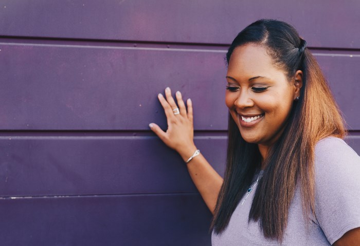 African American woman smiling against a purple wall