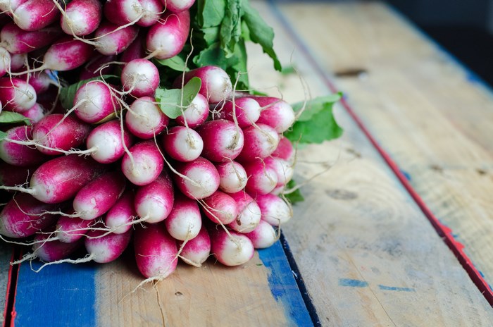 Bunch of fresh radishes on a wooden plank