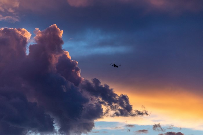 Airplane flying through a cloudy sunset sky