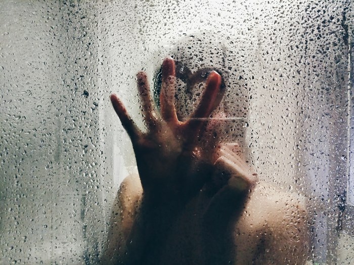 Person drawing a heart on a steamy shower glass