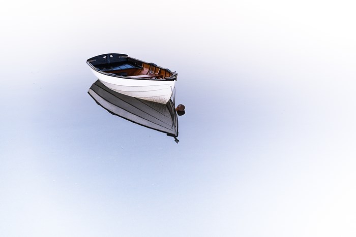 Minimalist boat reflected on clear water