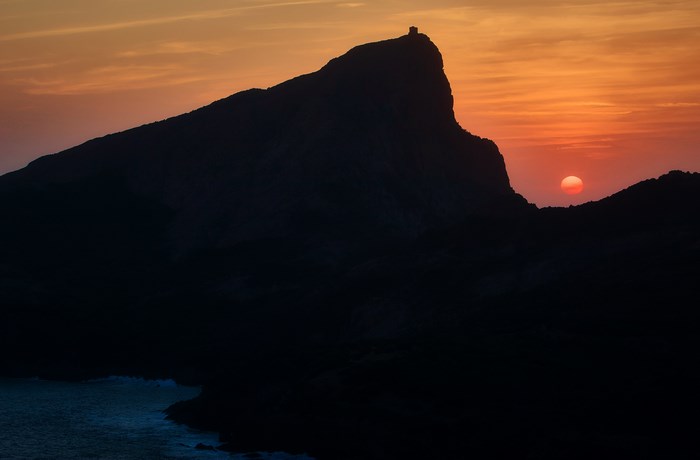 Silhouette of a mountain with a tower at sunset