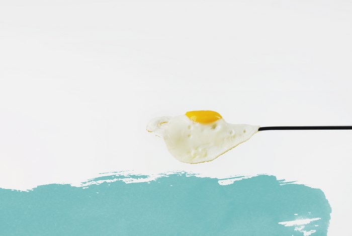 Fried egg on a black stick with blue paint splash