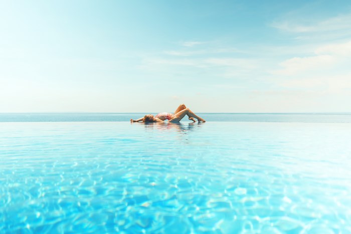 Woman Relaxing on Infinity Pool by the Ocean