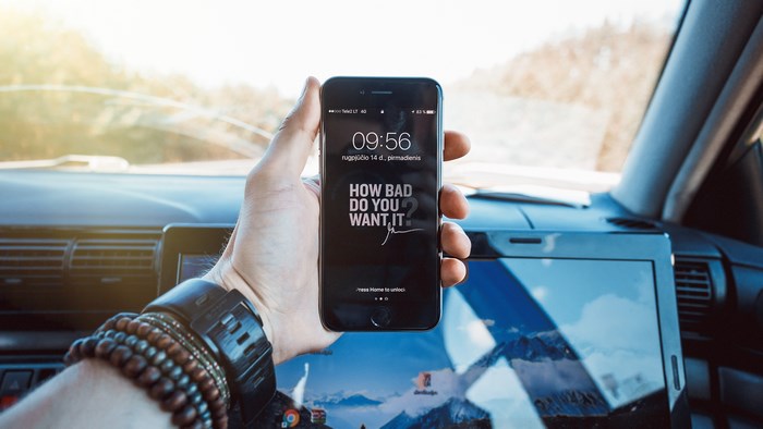 Man holding iPhone with Gary Vaynerchuk quote in car