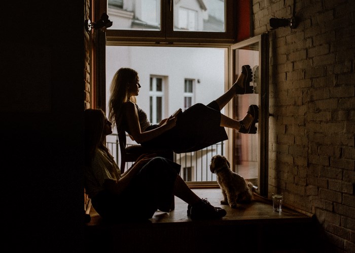 Two women and a dog relax by a window