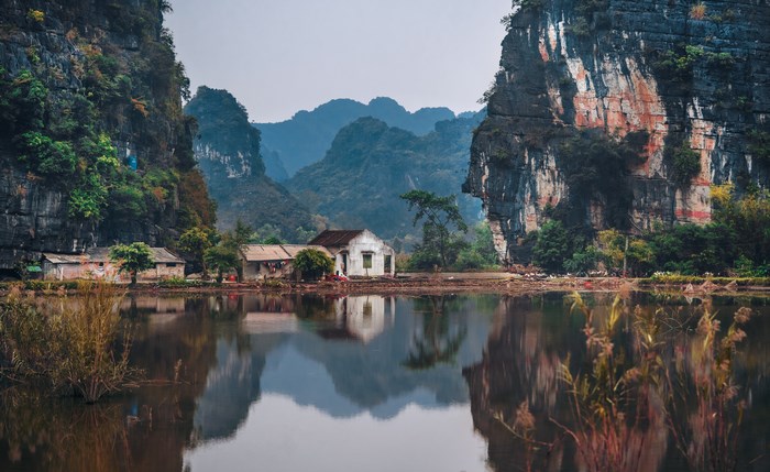 Tranquil Mountain Village with Reflective Water and Cliffs