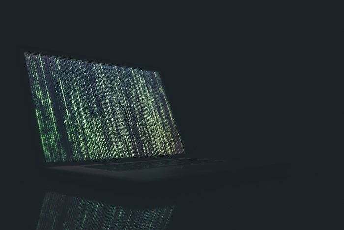 Laptop displaying green matrix code on screen