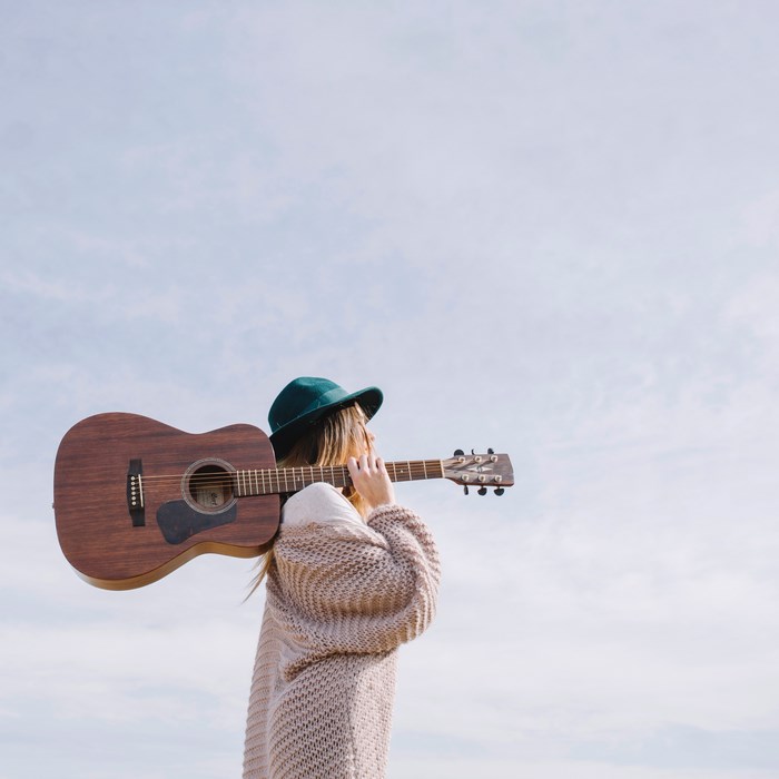 Woman in hat holding a guitar outdoors