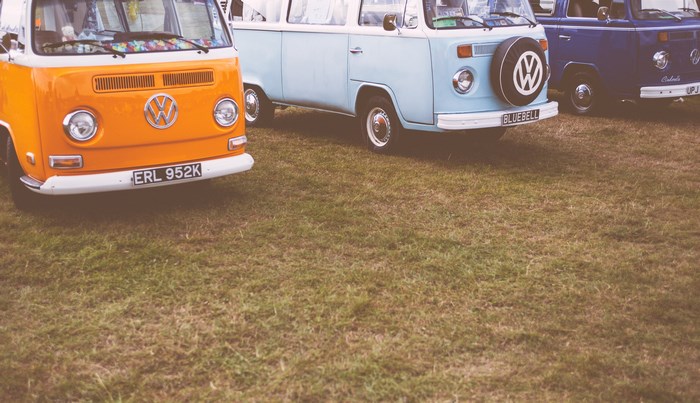 Three Volkswagen vans parked on grass