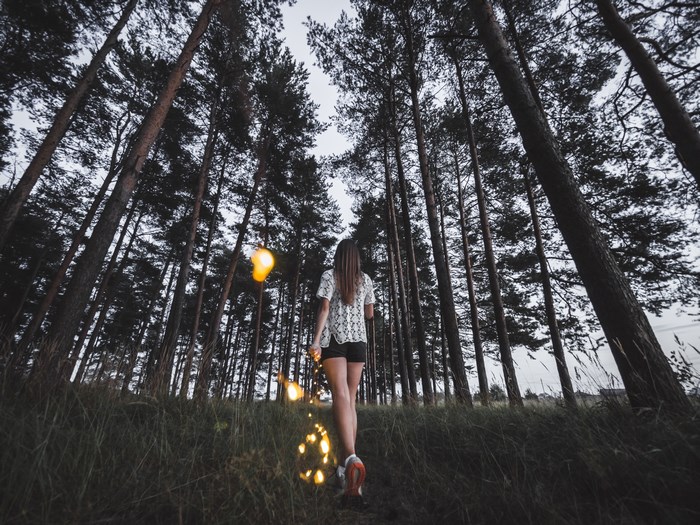 Woman walking in a forest with illuminated lights