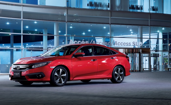Red Honda Civic Sedan in front of modern building