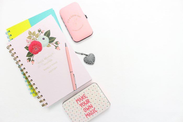 Pink notebook with floral design, pen, and jewelry