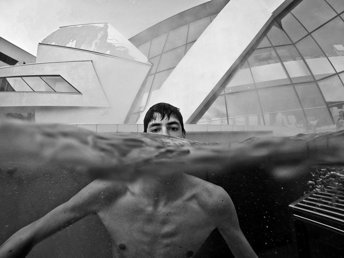 Man swimming in pool with modern building background