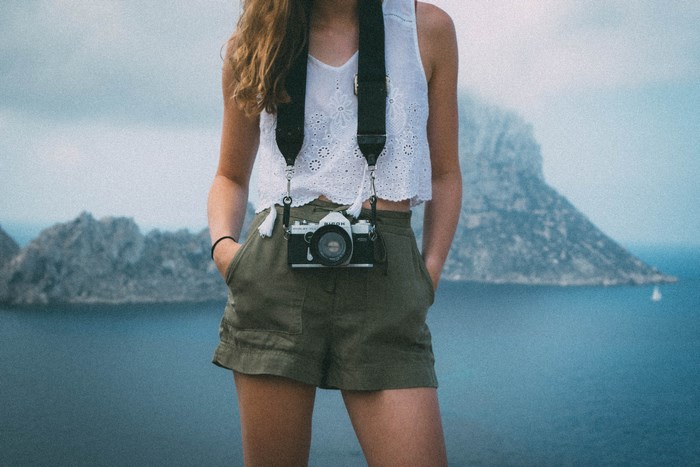 Woman with camera on island overlooking the sea