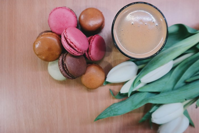 Colorful macarons with coffee and white tulips