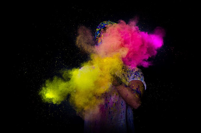 Person covered in yellow and pink holi powder