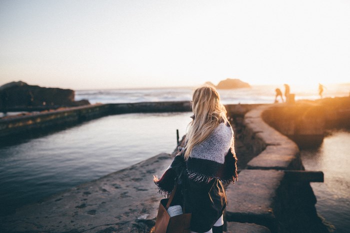 Woman in shawl by the ocean at sunset