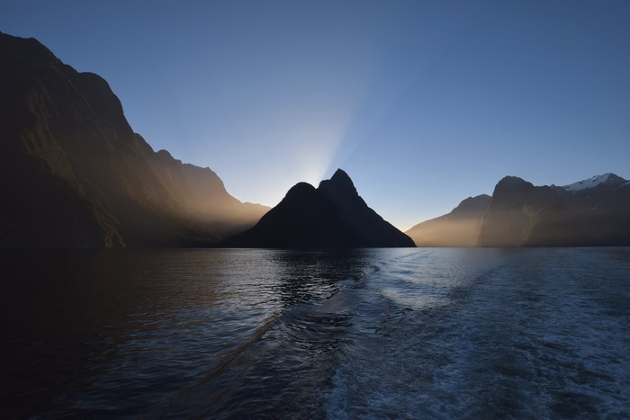 Sun rays behind a mountain in a fjord