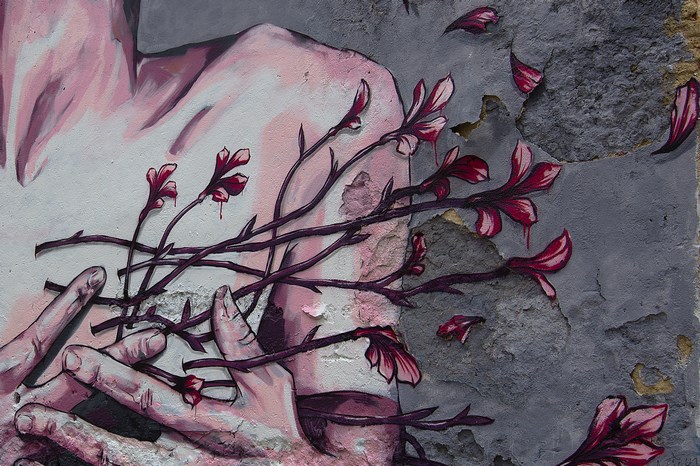 Street art mural of a body with flowers on a dilapidated wall