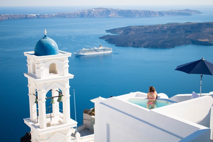 Woman in Pool Overlooking Sea and Cruise Ship in Greece