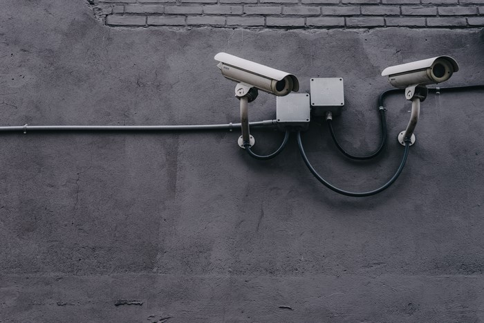 Two security cameras mounted on a grey concrete wall