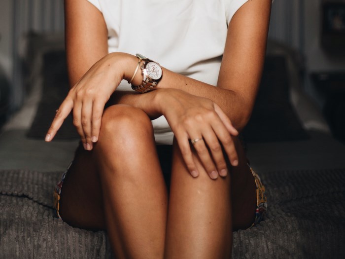Woman wearing a watch and ring sitting on a bed