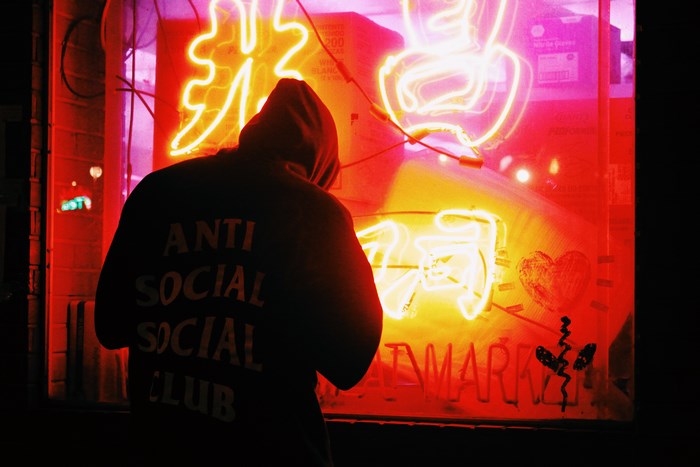 Person in hoodie in front of Chinese neon sign