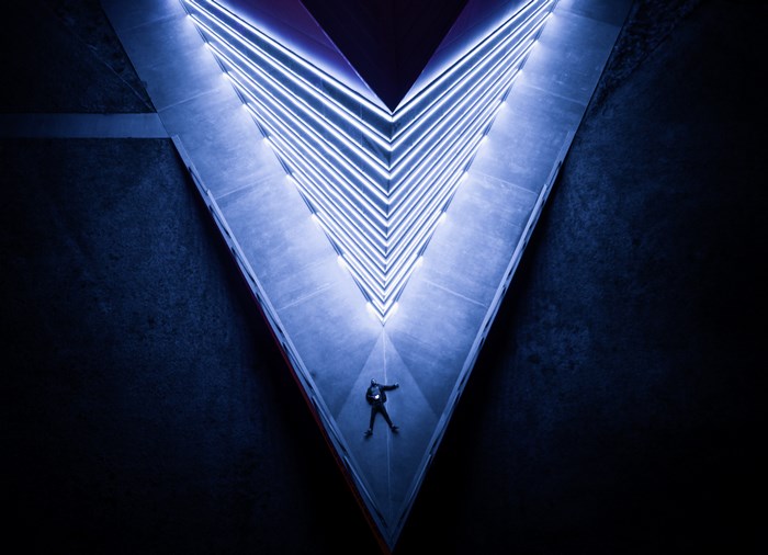 Person lying down in a V-shaped modern architecture with blue lights